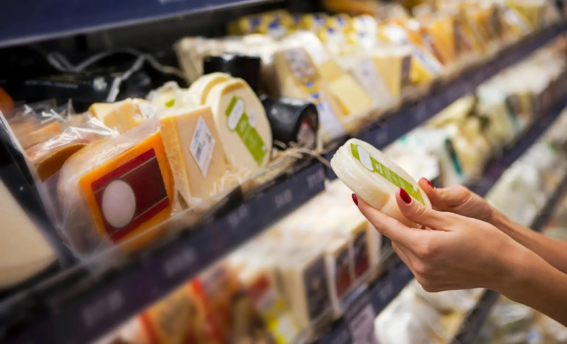 Woman's hands selecting cheese in store.