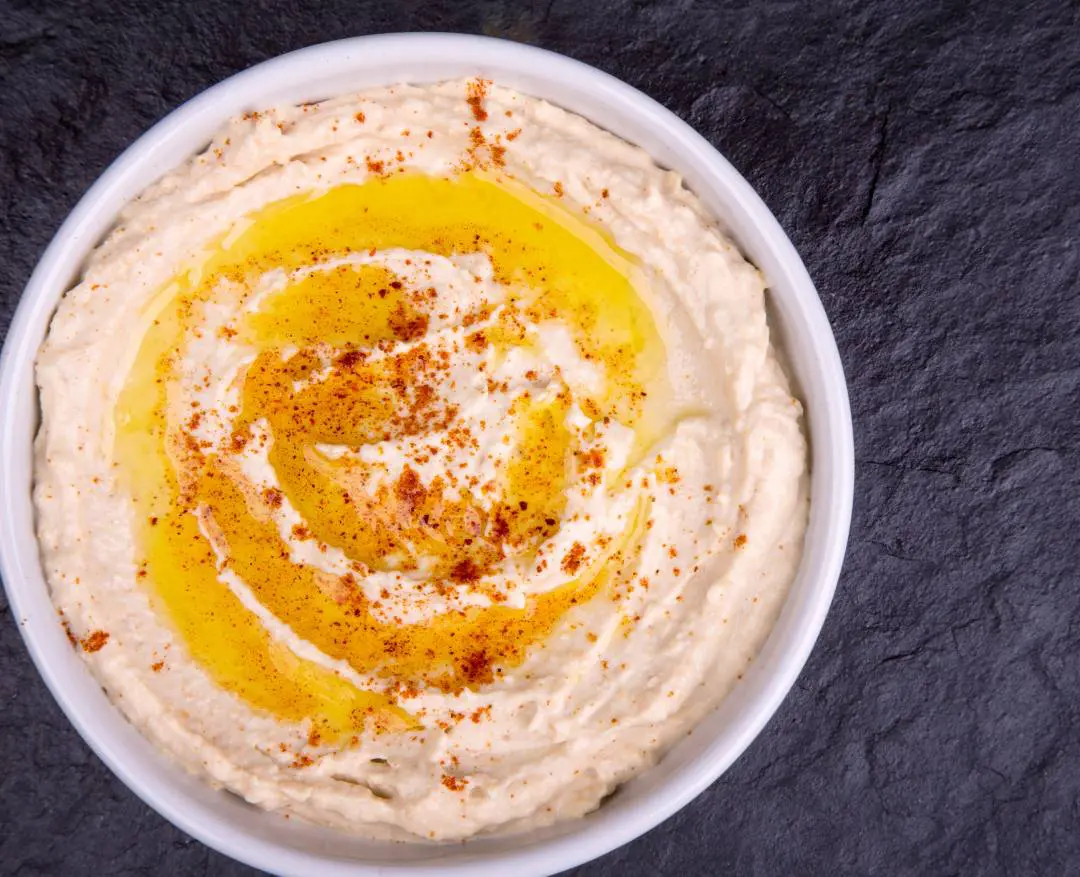 A bowl of hummus with spices on top.